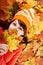 Girl in autumn orange hat on leaf group.
