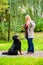 Girl in autumn park training her dog in obedience