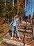 A girl on the background of an autumn park stands on wooden steps holding on to a copper cable