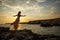 The girl on the background of a beautiful seascape and sunset, silhouette of a girl on a cliff, on a cliff,