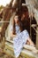 Girl on the background of an old thrown wooden house. girl in white dress with blue embroidery flowers