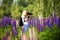 A girl with a backpack in a clearing with blooming flowers lupins in the forest photographs