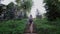 A girl with a backpack climbs up the old stone stairs through the coniferous park on the mountain