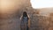 Girl with backpack explores ancient desert ruins. Pretty woman walks among mountain fortress walls in Masada, Israel. 4K