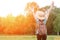 Girl with backpack and hat stands back with hands up against the forest. Toning