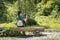 Girl with a backpack near the forest takes a photo on a smartphone. Back view. Summer sunny day