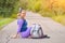 Girl with a backpack sits on the road near the curb, travel and tourism concept