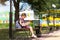 Girl with a backpack sitting on a bench and reading a book near the school. Back to school, lesson schedule, a diary with grades.