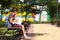 Girl with a backpack sitting on a bench and reading a book near the school. Back to school, lesson schedule, a diary with grades.