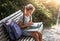 Girl with a backpack sitting on a bench and reading a book near the school. Back to school, lesson schedule, a diary with grades.