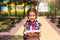 Girl with a backpack and a stack of books near the school. Back to school, happy pupil, heavy textbooks. Education, primary school