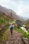 Girl with backpack walking down along the trekking route to verdant Xo-Xo valley. Mountain peaks and local village is