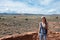 girl with backwards cap in the arid desert in summer, she carries her backpack and photo camera