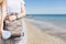 Girl with bag in hands is standing onear sea. View of the gray T-shirt and bag with big blue stick