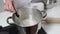 A girl baker, in uniform, measures the temperature with a thermometer in syrup for baking cakes and desserts for the