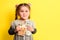 Girl with banknotes in hands on a yellow background, business child with world currency.
