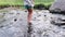 a girl with bare feet walking on a fast river among stones.