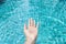 Girl bare hand over clean and crystal clear swimming pool water background