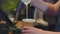 Girl barista adds hot milk pouring into paper glass closeup