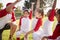 Girl baseball team kneeling with their coach, raising hands