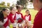 Girl baseball team in a team huddle with coach, listening