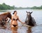 Girl bathe horse in a river