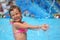 Girl bathes in pool under water splashes