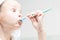 Girl in a bathing room fooling around with a toothbrush making an amazing face