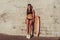 Girl in bathing suit summer city stands wall sunbathes sunglasses. Skateboard, relaxation after sport fitness, workout