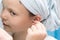 Girl in the bathroom cleans her ears with a cotton swab, close-up