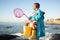 Girl, beach and fishing net with bucket, water and rock pool for outdoor adventure with boots, smile and ocean. Black