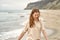 Girl on the beach have fun. Caucasian beautiful woman is happy on the beach against the background of the sea. Beige