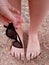 Girl on beach holds sunglasses in her hand, girlish legs on the sand