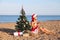 Girl on beach sits Christmas tree resort cocktail