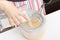 Girl beats with a mixer chicken eggs with sugar in a bowl in the kitchen