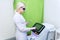 Girl beautician with blond hair adjusts the device for hair removal with a laser. Cosmetic equipment device.