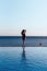 Girl in a beautiful bathing suit at sunset by the sea holding sunglasses