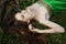 Girl in a beautiful green dress lies on the grass near the roots of a tree and dreams. Woman with bright makeup in nature, natural