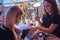 Girl in a beauty salon, using a phone while manicure master doing beauty procedure