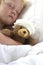 Girl in bed cuddling a teddy with bandage