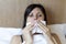 Girl in bed, Sinus pain, sinus pressure, sinusitis. Sad woman holding her nose and head because sinus pain. Sinus ache causing