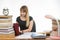 Girl behind the desk littered with books smiling in a laptop information gathering