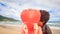 Girl behind Large Red Heart Guy Appears Kisses on Beach