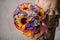 Girl in beige dress holding a bright bouquet of purple flowers,