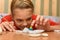 A girl bending over looks at a painted figurine made of salt dough