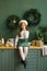 Girl in a beret sitting in the kitchen, decorated for Christmas and New Year and eating baguette