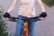 A girl in bicycle gloves holds her hand on the handlebars, clamping the brakes. A bicycle element on a street background.