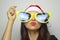 Girl with big funny sunglasses and Santa Claus hat celebrates Christmas