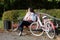 Girl on a bike ride in the autumn park. Sits on a bench. There is a bicycle nearby