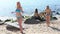 girl in bikini standing on beach while her friends are resting